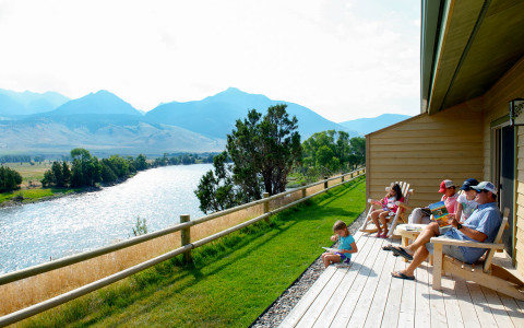a family sitting on a porch looking at the river