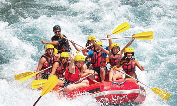 Group of people in helmets white water rafting