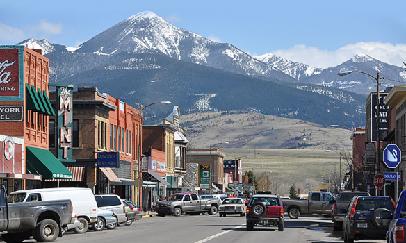 Row of shops in front of mountains in the town of Livingston Montana with cars driving down the road