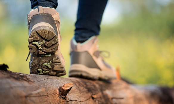 Close up shot of hiking shoes walking across a wooden log