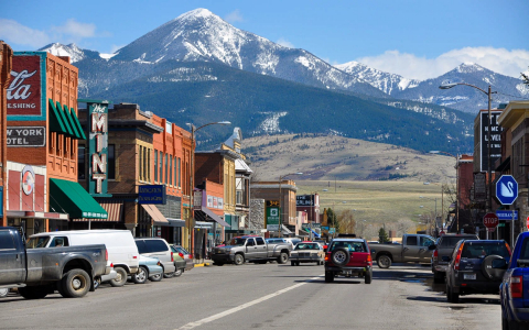 Row of shops in front of mountains in the town of Livingston Montana with cars driving down the road