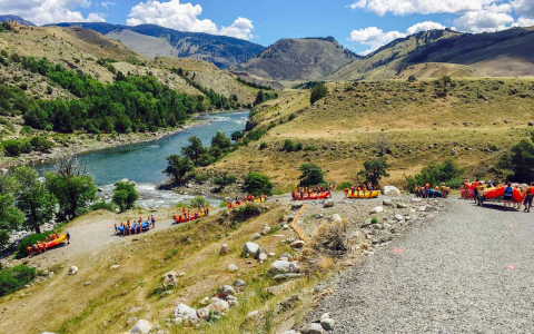Eight groups of people carrying rafts down a mountain to a river