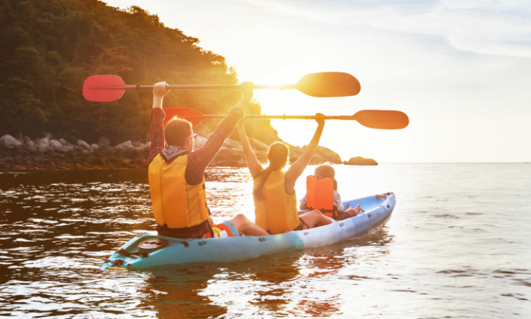 family of three kayaking at sunset