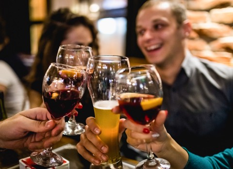 Group of friends clinking glasses with sangria and beer