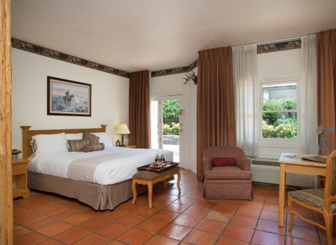 room with mexican tile floors, king bed, adjacent to double doors leading outside and seating area