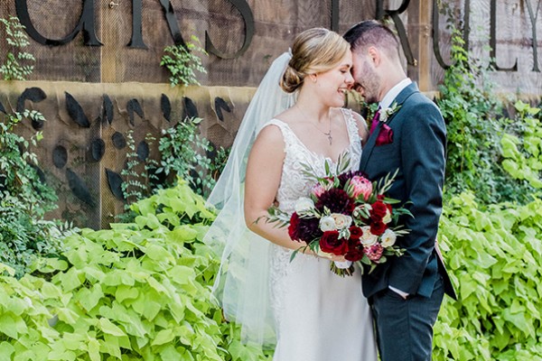 bride and groom laughing outside in front of yours truly sign