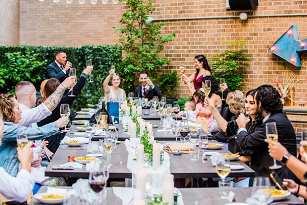 bridal party toasts with glasses of champagne while sitting at a table