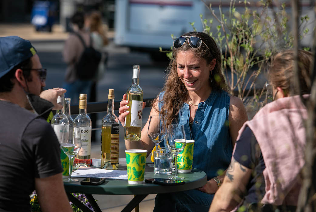 woman and friends sitting outdoors at mercy me drinking white wine