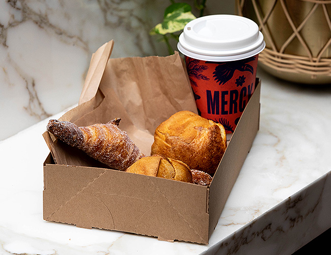 Box with croissants for breakfast and a to go coffee