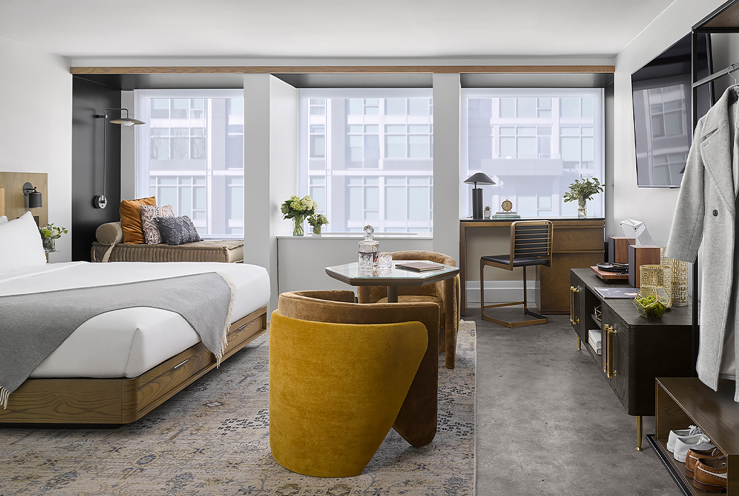 suite style hotel room with bed windows and a desk area