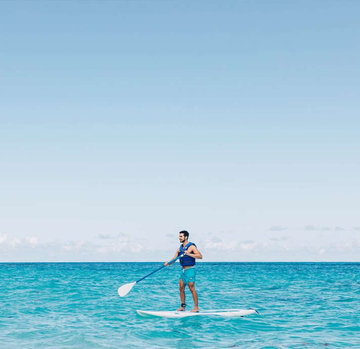 man paddel boarding in blue water 